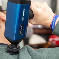 Person using massage gun on shoulder area